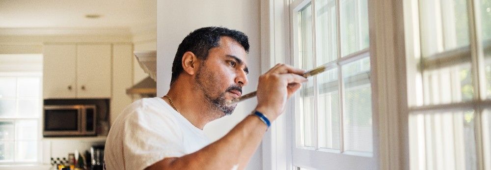 Mann streicht Fensterahmen